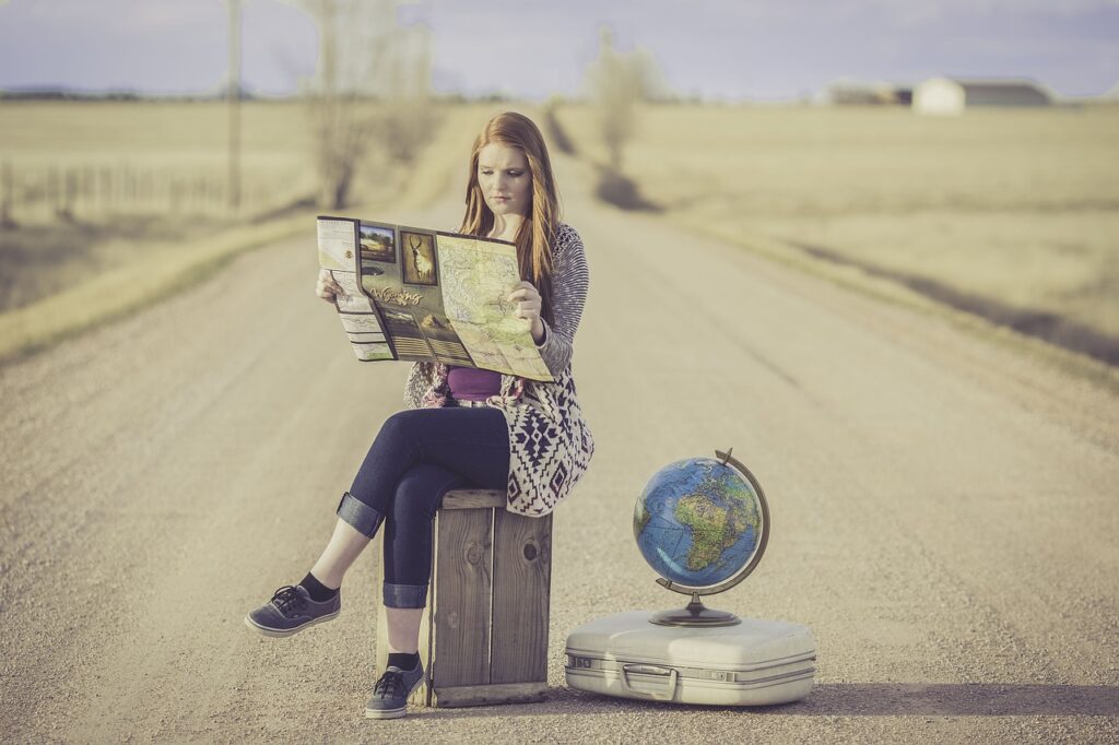 道に座り地球儀の横で地図を見る女性