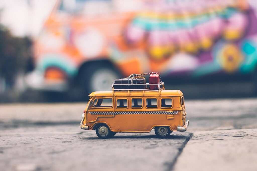 黄色いバスの上に荷物をのせて走っているおもちゃ