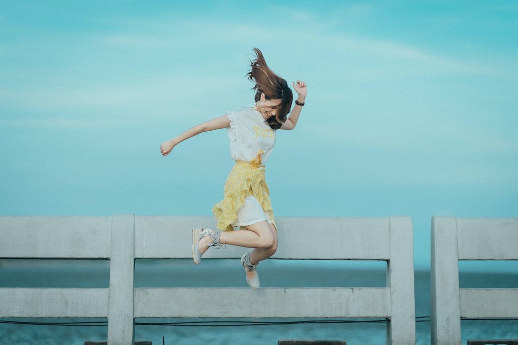 青い空の下で質素な格好でジャンプしている女性