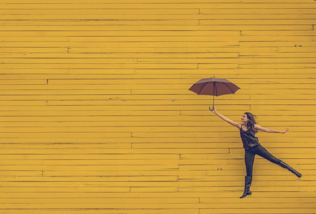 黄色の壁の前で傘をさしている女の人