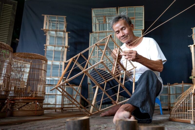 糸と木で器用に鳥かごを作る男性