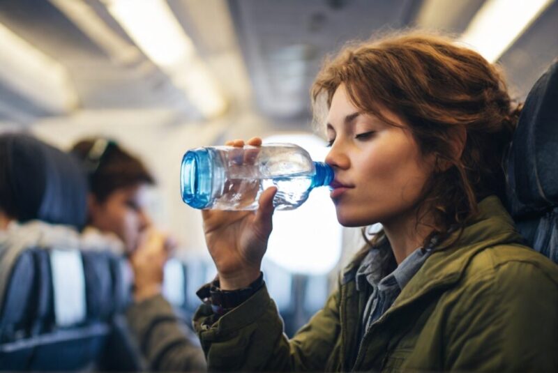 飛行機の中で水を飲む女の人
